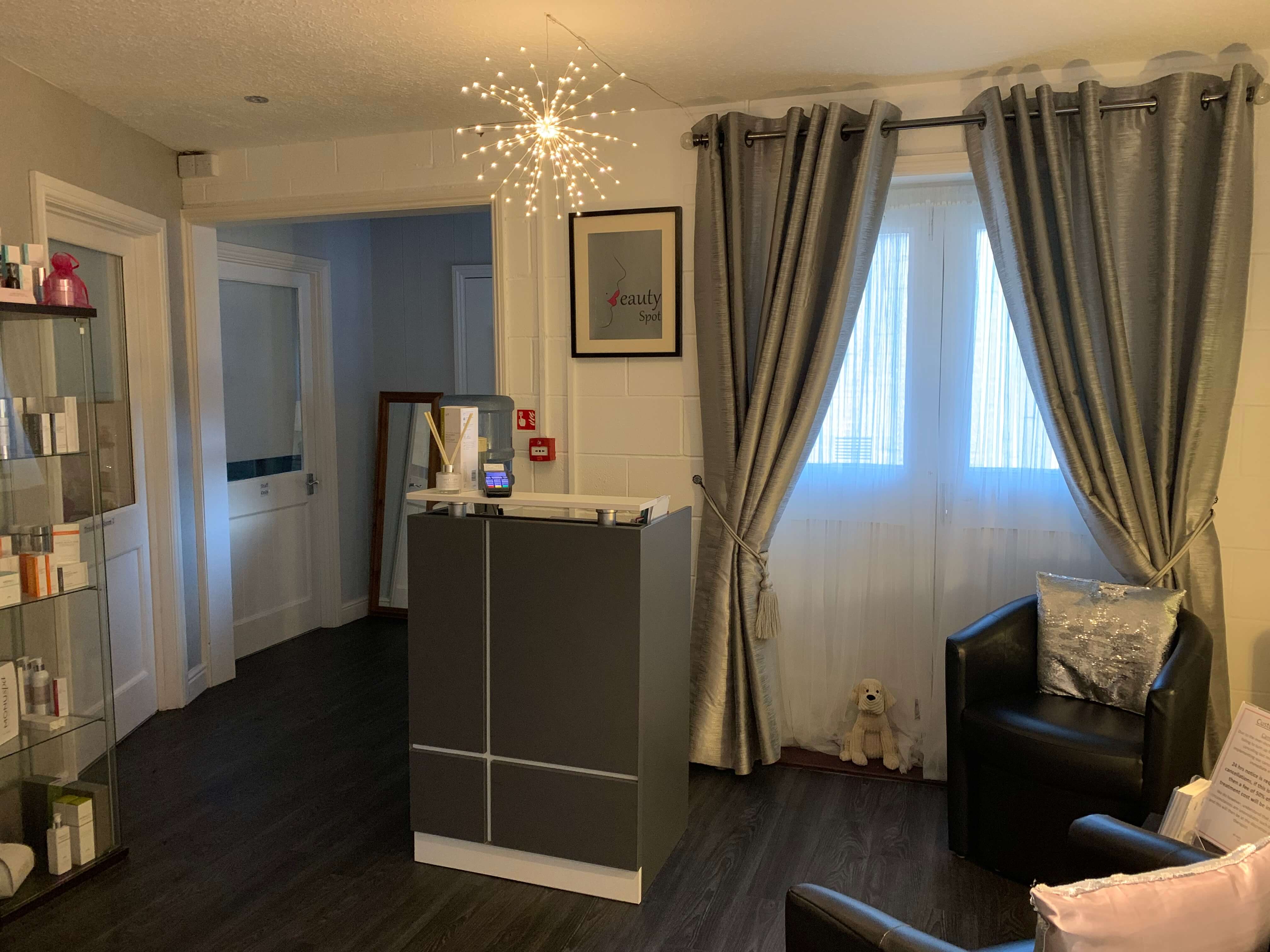 Beauty Spot reception with a grey desk and seating beside the window
